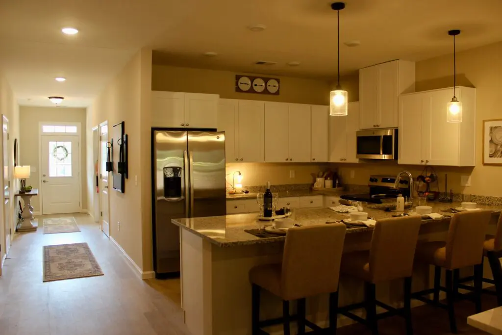 Modern kitchen with white cabinets, granite countertops, stainless steel appliances, and bar seating