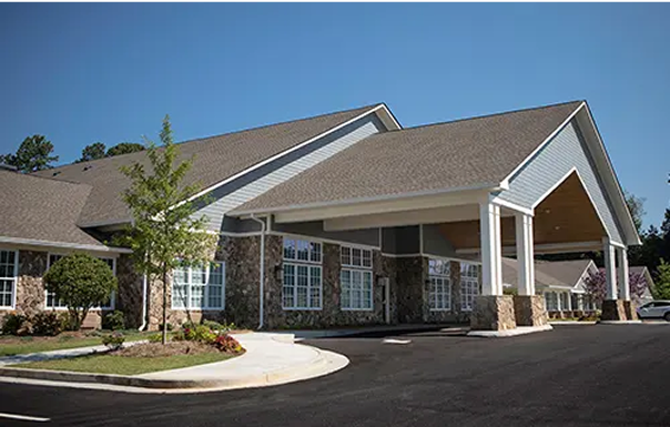 Exterior view of assisted living facility with landscaping and covered entrance on sunny day