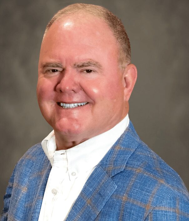 Smiling middle-aged man with gray hair wearing a blue plaid sports coat and white dress shirt