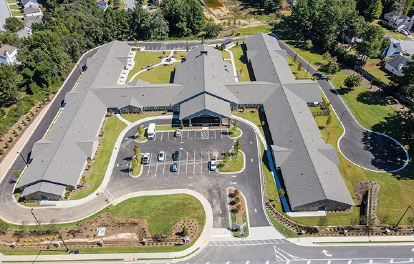 Aerial view of office building complex with parking lot surrounded by green space and trees