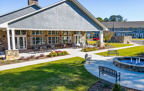 Retirement community center with outdoor patio, pool, landscaping, and apartment buildings
